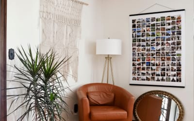 A giant 3x4 foot Engineer Print features a printed grid of 130 vacation photos. It is hanging in a stylish living room.