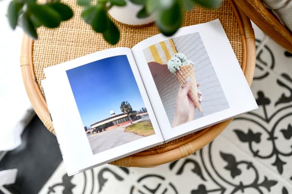 An open 8x8 inch hardcover photo book, shows vacation photos of a cute ice cream shop and a waffle cone of mint chip.
