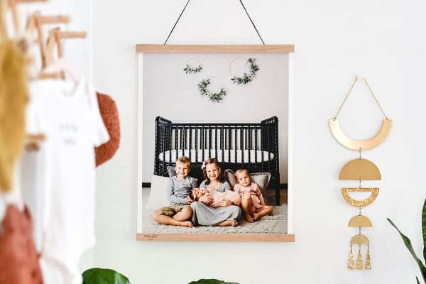 A Fine Art Print of a family portrait hangs from Oak Poster Rails in a child's bedroom.