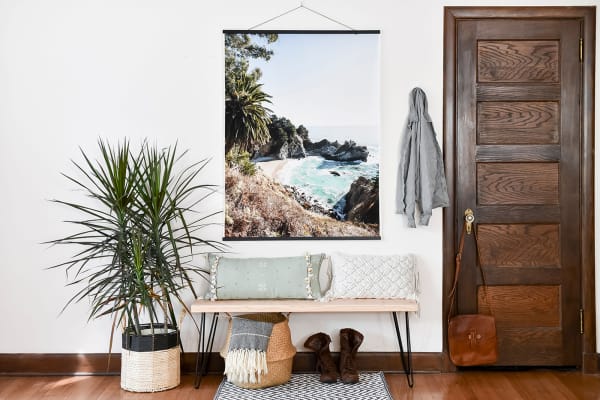 An Engineer Print of a tropical vacation view hangs from Black Poster Rails above an entryway bench