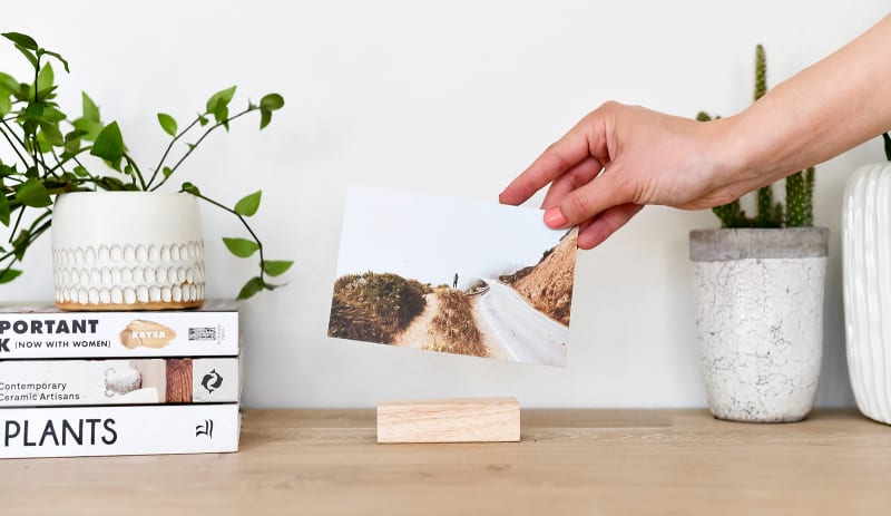 A Classic Print of a person standing on a foggy mountainside is displayed on a desk using a wood block.