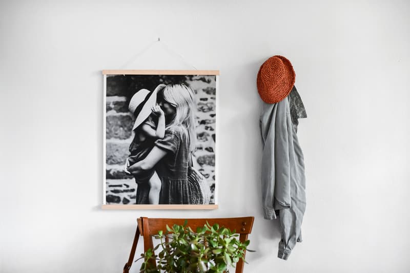 A black and white Fine Art Print of a mother and her daughter hangs on the wall above a plant.