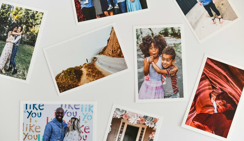 Several 4x6 Classic Prints with crisp white borders show off bright photos. They're scattered on a white background.