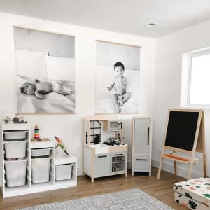 Two giant black and white Engineer Prints featuring baby photos hang in a playroom.