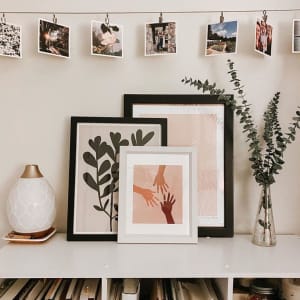 A collection of Square Prints on extra thick photo paper hang over several framed Fine Art Prints on a bookshelf.