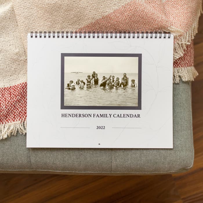 The cover of a Family History Wall Calendar shows a large family swimming and the title, Henderson Family Calendar 2022.