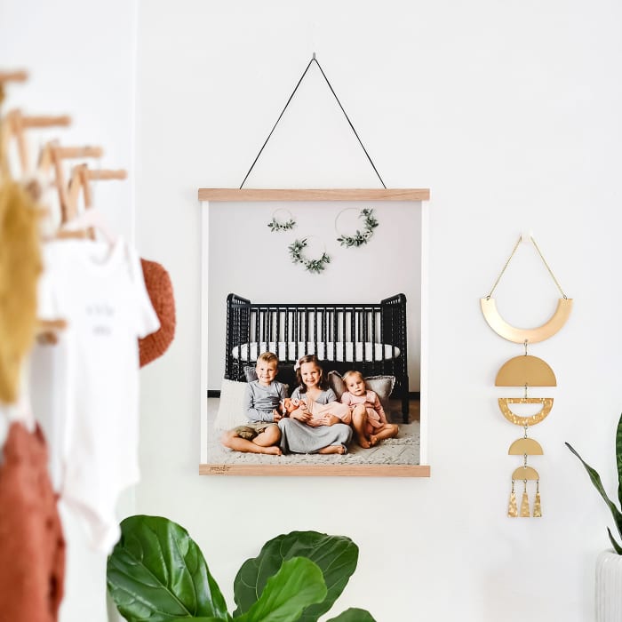 A Fine Art Print of a family portrait hangs from Oak Poster Rails in a child's bedroom.
