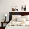 Two Fine Art Prints of vacation photos hang from Oak Poster Rails above a neatly made bed.