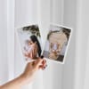 A hand holds out two 5x7 Classic Prints of a mom and baby, in front of a white curtain.