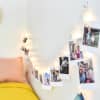 Clip Lights shine as they hold fun family photos over a bed, for cute custom bedroom decor.
