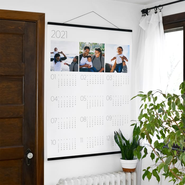 A Calendar hangs from 36 inch black Wood Poster Rails. The calendar has three photos along the top.