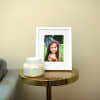 A portrait of a girls is displayed as a Framed Fine Art Print in a white matted frame, on an end table.