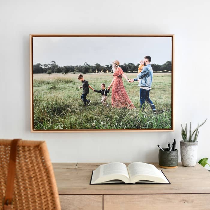 A family photo is displayed as a Floating Frame Canvas Print in Maple above a desk.