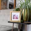 A Gold Square Frame and potted plant decorate a side table.
