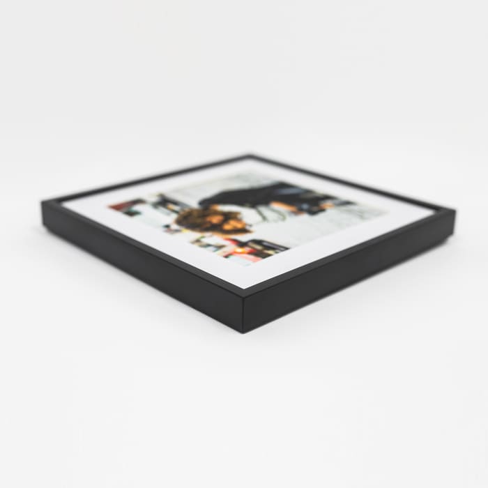 A single black framed photo print lays flat on its back to showcase the corner detail of the frame.