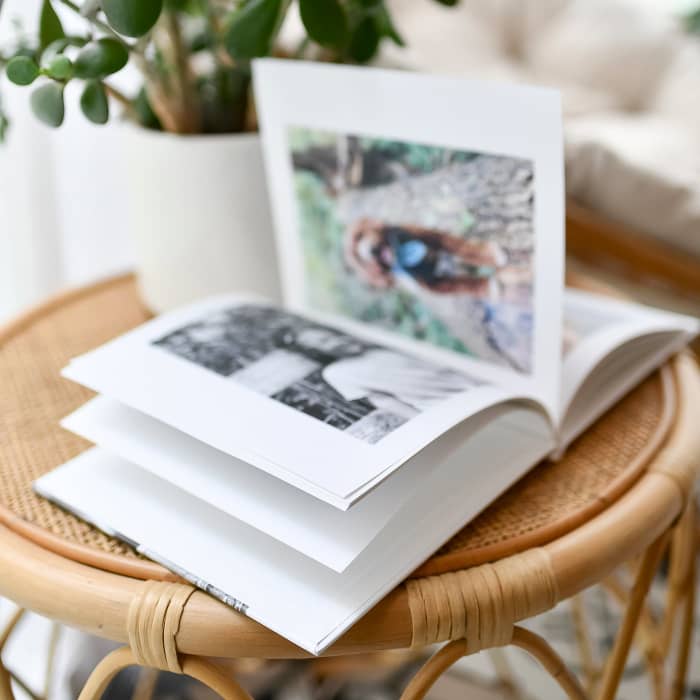 A Hardcover Photo Book lies open on a rattan side table.