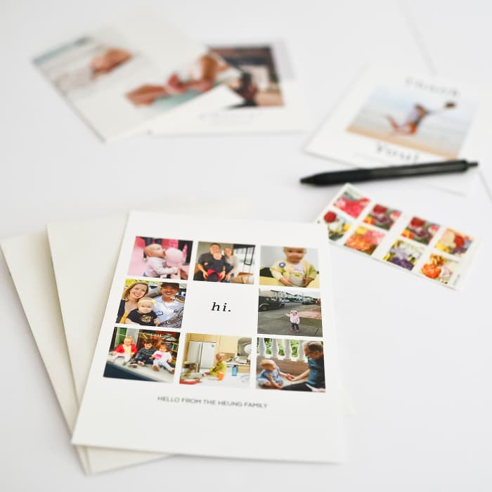 Photo Greeting Cards next to stamps and a pen. The card shows nine family photos, and reads Hello from the Heling family.