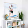 A Square Engineer Photo Print of a family on vacation hangs from Maple Poster Rails above a bookcase.