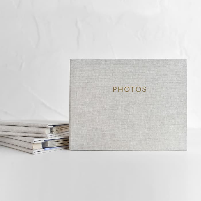 A 9x7 inch photo album with a creme colored linen cover and gold title reading, PHOTOS.