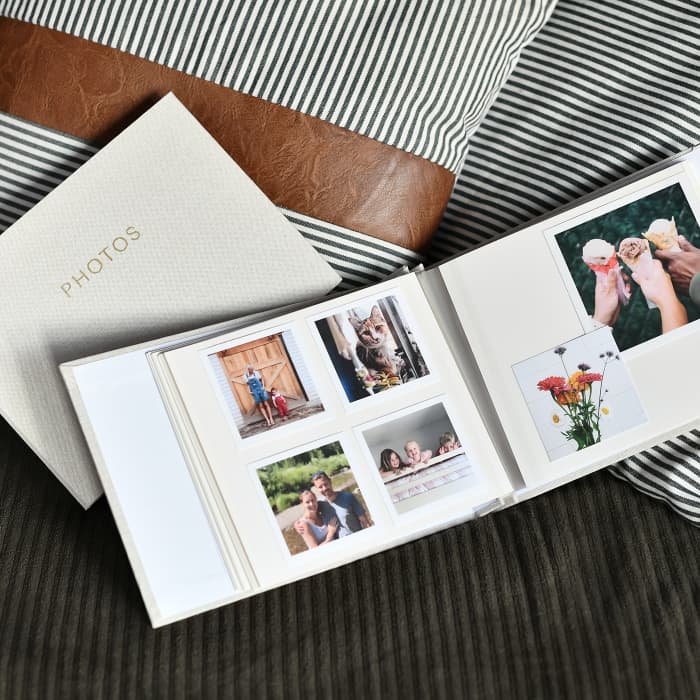 Various sizes of Parabo Press Square Prints are placed in the pages of a creme colored Linen covered photo album.