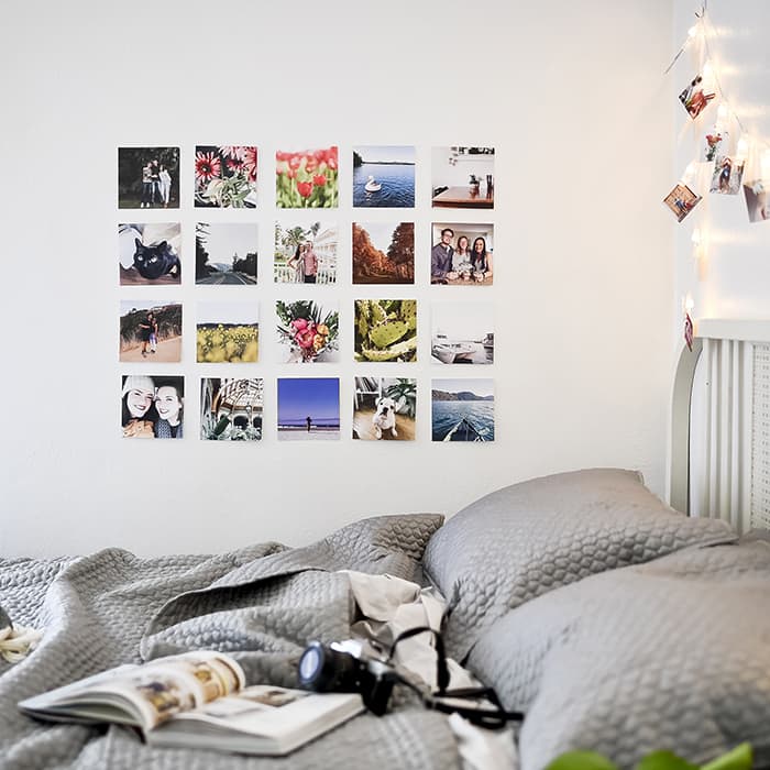 A grid of 20 Square Photo Prints decorates a wall above a bed.