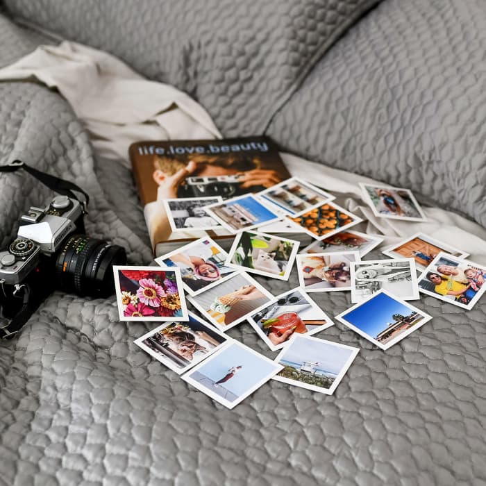 A set of 20 Tiny Prints showing vacation photos scattered across a shiny gray bedspread. 