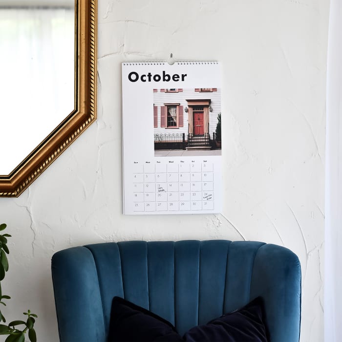 A Large custom Wall Calendar showing a vacation photo hangs above a blue velvet chair.