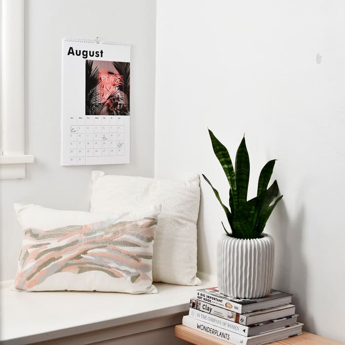 A Parabo Press custom photo Wall Calendar hangs above a cozy windowseat.