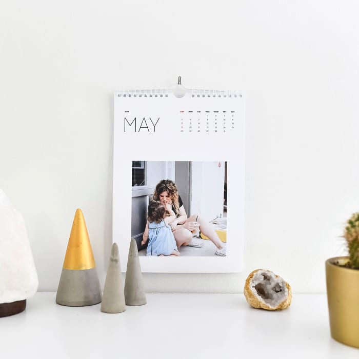 A Keepsake Wall Calendar showing a mother and daughter photos, hangs above a white desk.