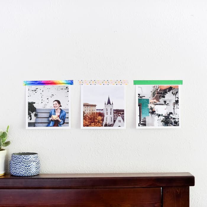 Three Square Photo Prints are taped above a bookshelf using colorful damage-free Washi Tape.